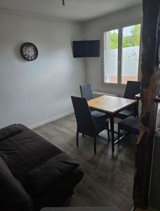 a living room with a table and chairs and a clock at Chez les chtis de vayrac in Vayrac