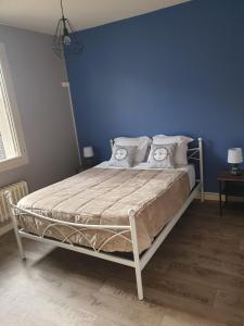 a bedroom with a bed with a blue wall at Chez les chtis de vayrac in Vayrac