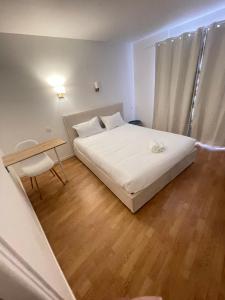 a small bedroom with a white bed and a wooden floor at Aparthotel New Palmarium in Amélie-les-Bains-Palalda
