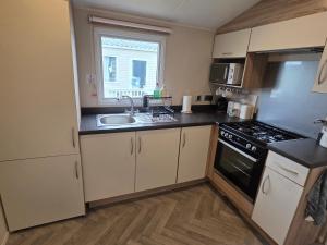 a kitchen with a sink and a stove top oven at Beachside caravan retreat - at New Beach, Dymchurch in Dymchurch