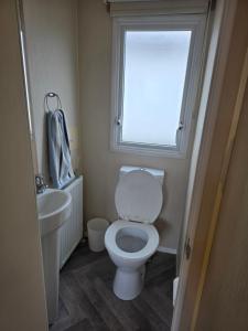 a bathroom with a toilet and a sink and a window at Beachside caravan retreat - at New Beach, Dymchurch in Dymchurch +28 photos