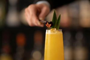 a person adding a garnishment to a yellow drink at COMO The Halkin in London