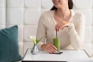 a woman is stirring a green drink on a table at COMO The Halkin in London