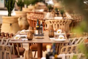 a wooden table with bottles of wine and chairs at Palazzo Artemide - VRetreats, an SLH Hotel in Syracuse
