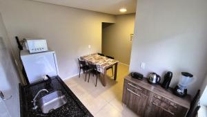 a kitchen with a sink and a table with a microwave at Ipê Eco Village, Apartamentos perto do Beto Carrero in Penha