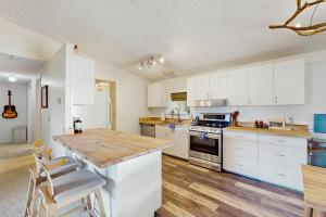 a kitchen with white cabinets and a wooden counter top at Hill House in Belfair +20 photos