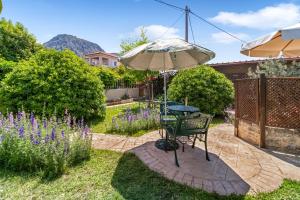 a table and an umbrella in a garden at Ancient Corinth Guest House in Korinthos
