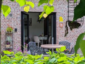 a patio with a table and chairs in front of a brick building at Aska Logies vakantiewoning in As