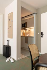 a room with a table with a suitcase and a kitchen at Bob W Munich City West in Munich