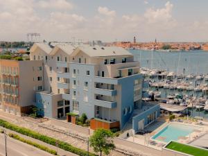 an apartment building with a pool in front of a marina at Mosella Suite Hotel - A Lagoon Retreat in Sottomarina