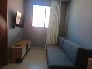 a living room with a blue couch and a window at Vila Atlântida BEACH FLAT 311B in Luis Correia