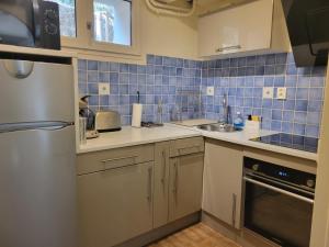 a kitchen with white cabinets and blue tiles on the wall at appartement leauma in Guillestre