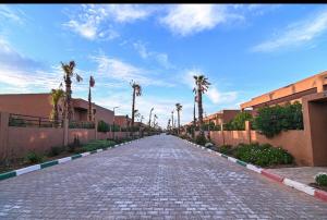 a cobblestone street with palm trees and a building at The Oasis Marakech in Marrakesh