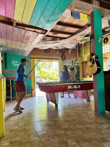a woman playing ping pong in a pool table at Hostel Bamaica Algodoal - Espaço Curupira in Algodoal