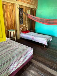 a room with two beds and a hammock in it at Hostel Bamaica Algodoal - Espaço Curupira in Algodoal