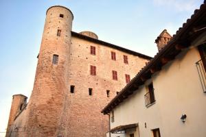 a large brick building with two towers next to a building at Langhem Suites Luxury Apartments in Castiglione Falletto