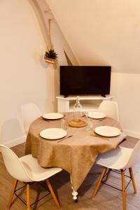 a dining room table with white chairs and a television at Escapade au Mont St Michel in Pleine-Fougères