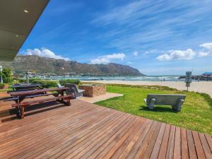 a deck with picnic tables and a bench on the beach at 8 On Fleur Park Beach in Gordonʼs Bay
