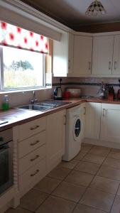 a kitchen with a sink and a washing machine at Teach Eamonn in Annagry