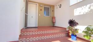 a porch with a white door and a plant at Tabarca - Chalet con jardín y piscina comunitaria in Peniscola