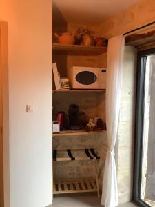 a kitchen with a shelf with a microwave and a window at Damvix Chambre d hôtes La Barbée in Damvix