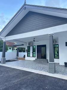 a large white building with a large garage at Homestay Anaza in Kampong Balai Maras
