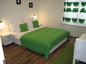 a bedroom with a bed with a green blanket on it at Eva Luxury Rooms & Apartments in Plitvička Jezera