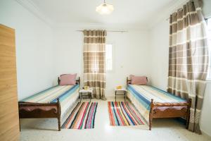 a bedroom with two beds and a rug at Villa Bianca 2 in Fafou