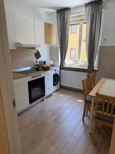 a kitchen with white cabinets and a table and a table and chairs at Appartamenti Camere Schaefer in Tarvisio
