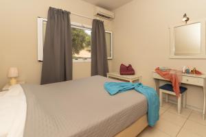 a bedroom with a bed and a desk and a window at Dion Zois in Finikounta