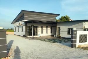 a small white house with a driveway at Azlynie Homestay in Kangar