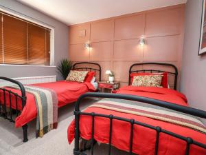 two beds in a bedroom with pink walls and red sheets at Steam and Stay Hoole in Chester
