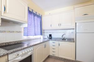 a kitchen with white cabinets and a sink and a refrigerator at OBSIDIAN Granada Park in Arona +2 photos