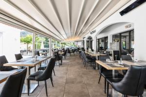 a dining room with tables and chairs and windows at Comfort Aparthotel Mandelieu la Napoule Village in Mandelieu-La Napoule