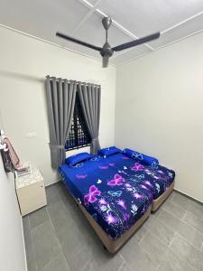 a bedroom with a blue bed with pink flowers at Homestay Anaza in Kampong Balai Maras