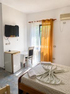 シェンジンにあるAdriatic Residence Shengjinのベッドと机とテレビのある寝室