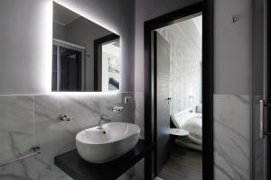 a bathroom with a white sink and a mirror at La Palazzata Urban Suites in Messina