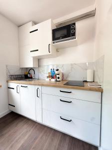 a white kitchen with white cabinets and a microwave at Apartament Flauta in Mikołajki