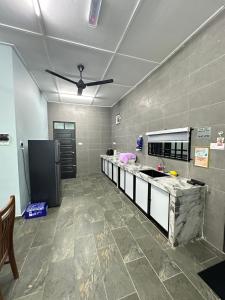 a kitchen with a counter and a ceiling fan at Homestay Anaza in Kampong Balai Maras