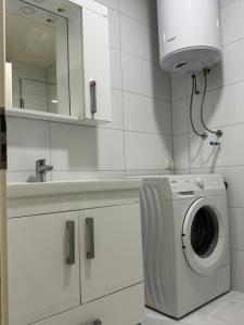 a white bathroom with a washing machine and a mirror at Fiona's apartment in Gjakove
