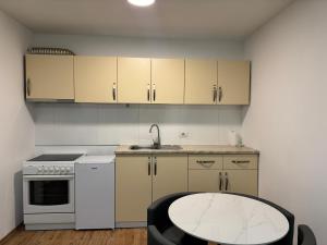 a kitchen with white cabinets and a sink and a table at Fiona's apartment in Gjakove
