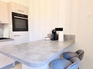 a kitchen with a counter with two blue chairs at Appartement 2 prsn Proche Gare Viotte in Besançon +8 photos