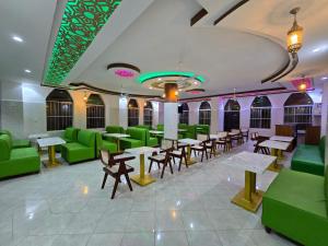 a restaurant with green chairs and tables and benches at Lamu Creek Hotel in Lamu