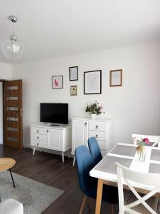 a living room with a television and a table and chairs at Apartament Flauta in Mikołajki