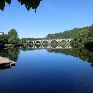 a bridge over a river with a reflection in the water at Casa da Miquinhas II in Ponte da Barca