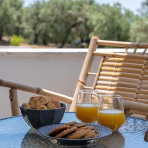 a table with a bowl of cookies and two glasses of orange juice at Jimmy's Guest House Skiathos in Skiathos