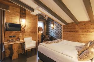 a bedroom with a bed and a desk and a television at Hotel Astoria in Fiera di Primiero