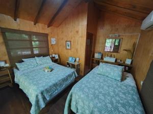two beds in a bedroom with wooden walls at Jimmys cabins in La Periquera