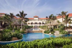 a resort with a swimming pool and palm trees at Sheraton Haikou Hotel in Haikou