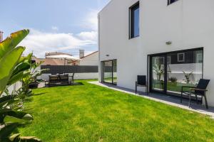 a backyard with green grass and a white house at Poolside oasis by Caparica beach in Charneca